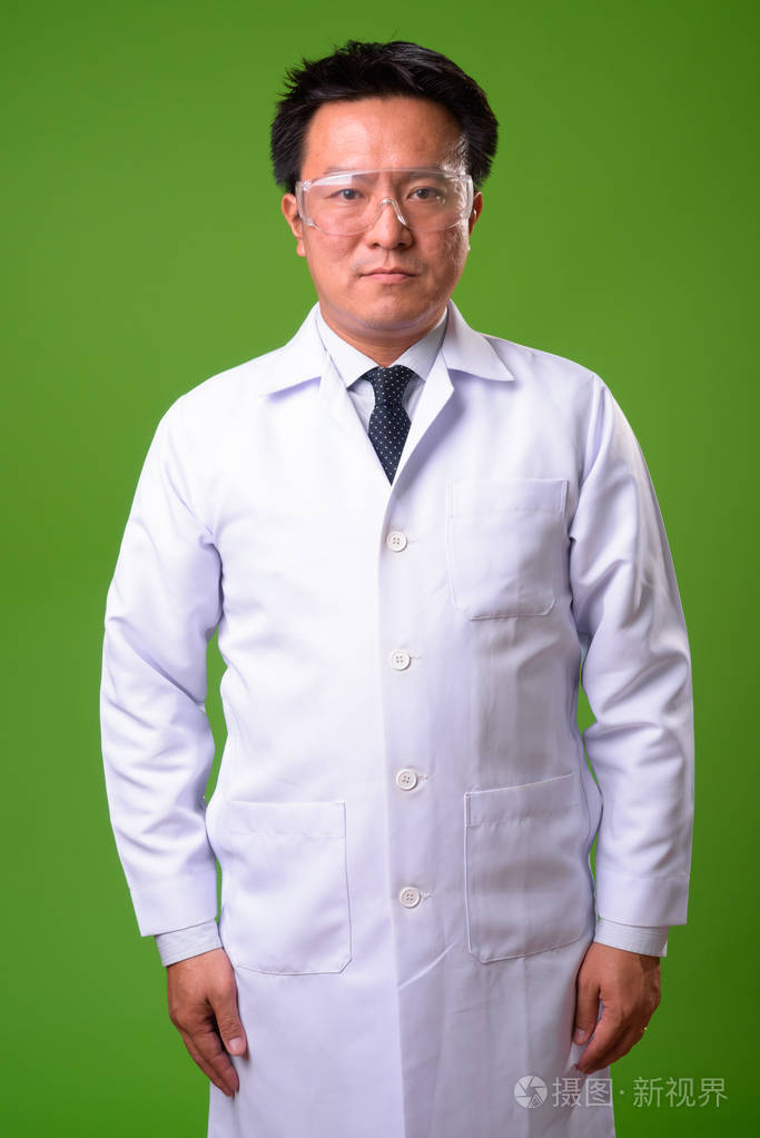 成熟的日本男人医生在绿色背景下戴防护眼镜