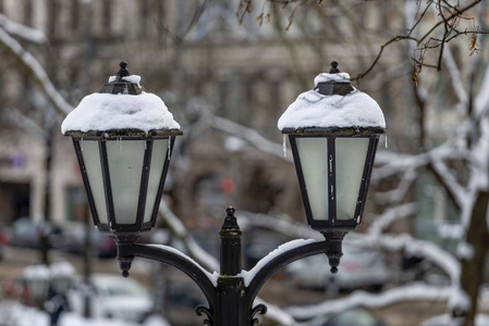 白雪覆盖了古老的灯笼，背景是城市公园。