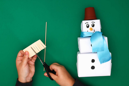 最初设计的三件圣诞礼物白纸，一条缎带，以雪人的形式出现在绿色的背景上。 一步地在照片上。 手工DIY。 礼物中的雪人