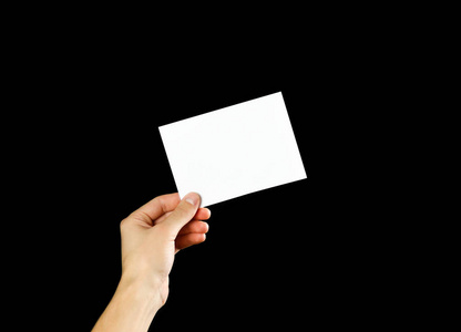 黑色的空白单张手拿空白小册子在手中. 孤立在黑色背景上.