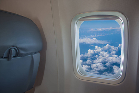 美丽的景色从飞机的窗户到蓝天，白云在阳光明媚的日子从乘客座位。 假期乘飞机去欧洲旅游