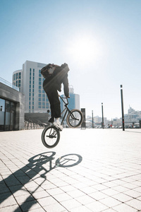 在阳光明媚的日子里，BMX骑手在城市风景的背景下跳上自行车。BMX概念。 bmx的街头自由泳