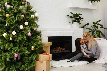 母亲和女儿戴格特坐在客厅壁炉和圣诞树附近的地板上