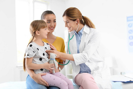 s doctor examining little girl near parent in hospital