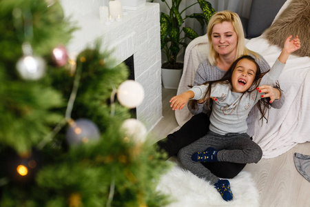 母亲和女儿戴格特坐在客厅壁炉和圣诞树附近的地板上