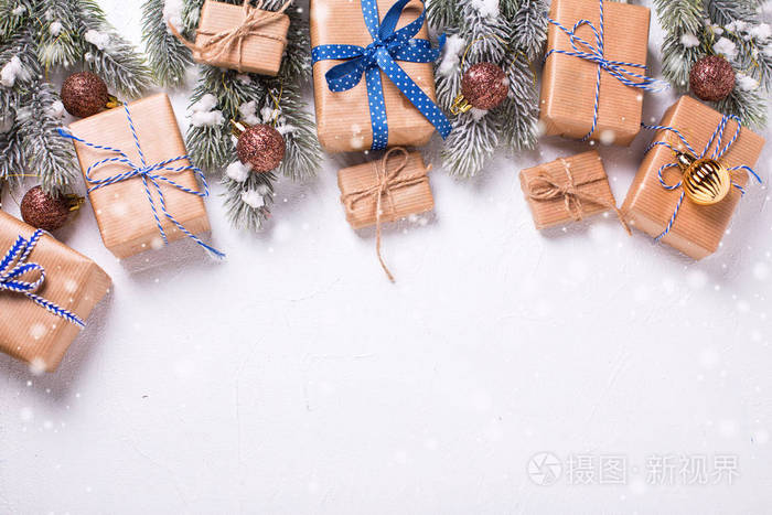 包裹圣诞节的边界呈现棕色的球和毛皮树枝在白色纹理背景。 选择性聚焦。 上面的风景。 文本地点