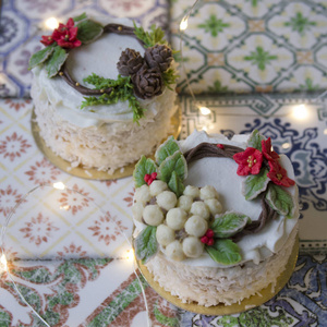 白色新年或圣诞蛋糕装饰奶油一品红花，松果，棉花和云杉枝在五颜六色的桌子上。 冬天出生的人的生日蛋糕。 复制空间选择性聚焦