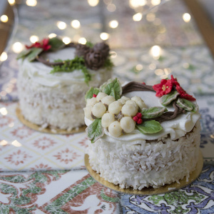 白色新年或圣诞蛋糕装饰奶油一品红花，松果，棉花和云杉枝在五颜六色的桌子上。 冬天出生的人的生日蛋糕。 复制空间选择性聚焦