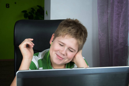 肥胖的小男孩坐在电脑前听音乐。