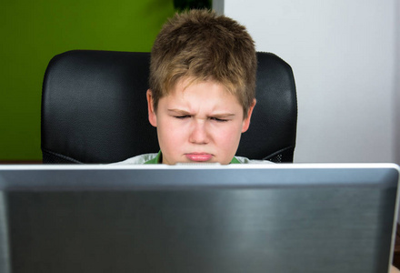 肥胖的小男孩坐在电脑前。