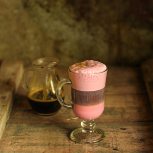 拿铁菜甜菜汁粉红色咖啡与牛奶在一个透明的杯子在桌子上。