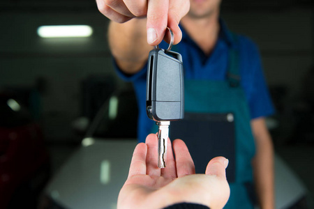 年轻的汽车服务技术人员给客户钥匙。