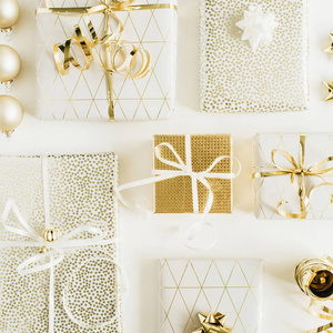 礼品盒，白色背景上有蝴蝶结和金色装饰品。 新年圣诞节节日平躺顶景构图。