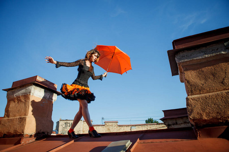 带着雨伞在屋顶上的年轻漂亮的女人。 浪漫的散步模特女孩在天空背景