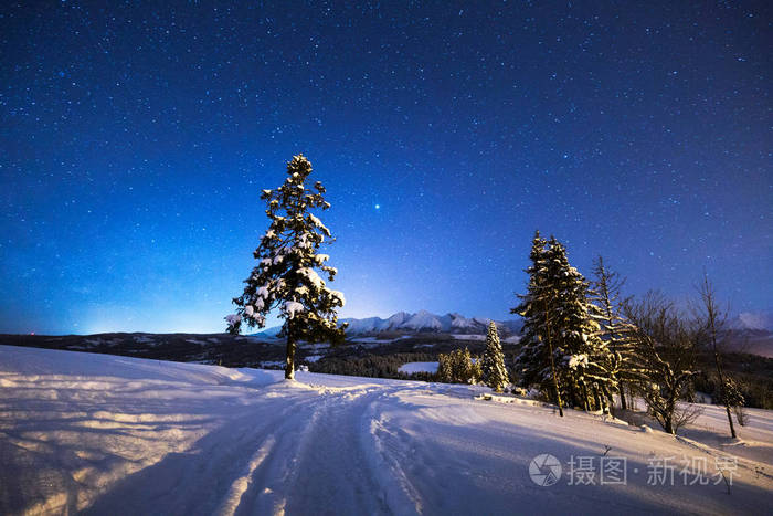 冬天的夜晚风景冬天的路在群山的蓝夜天空下充满了星星冬季山地自然
