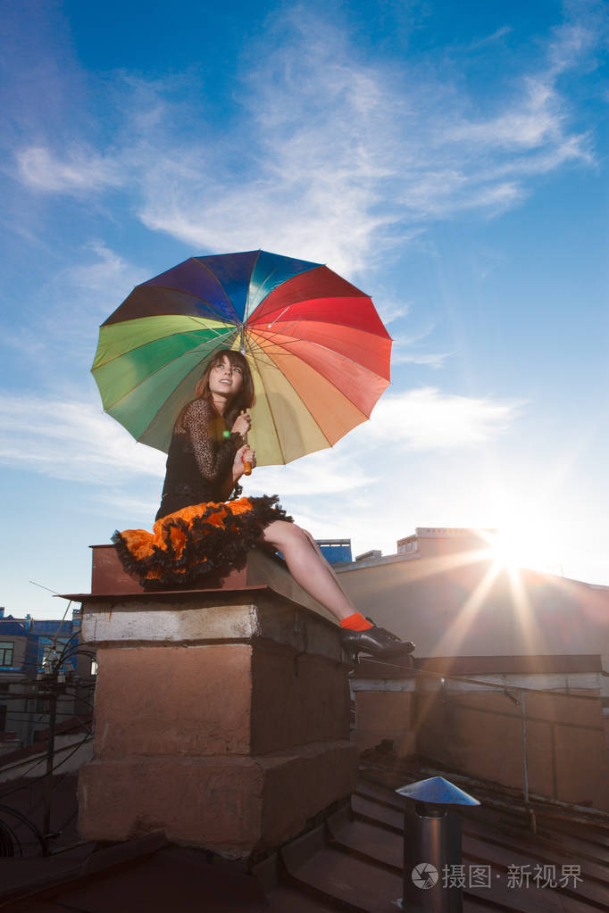 带着雨伞在屋顶上的年轻漂亮的女人. 浪漫的散步模特女孩在天空背景