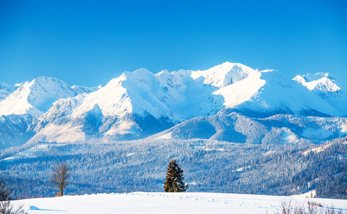 雪山景观。 滑雪胜地的自然背景。 在一个明亮的冬天，白色的山峰和小山覆盖着雪。 冬天群山上纯净清澈的蓝天。