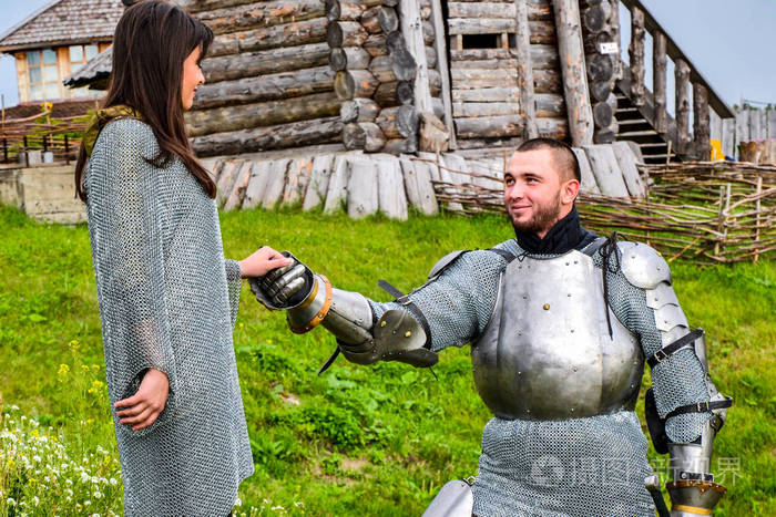 一位身穿盔甲的骑士跪在他的女士心前骑士盔甲和武器半古董照片