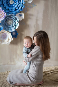 母亲节快乐。 可爱的快乐女人与婴儿摆在时尚的现代工作室装饰。 卡片海报横幅设计元素及其他用途
