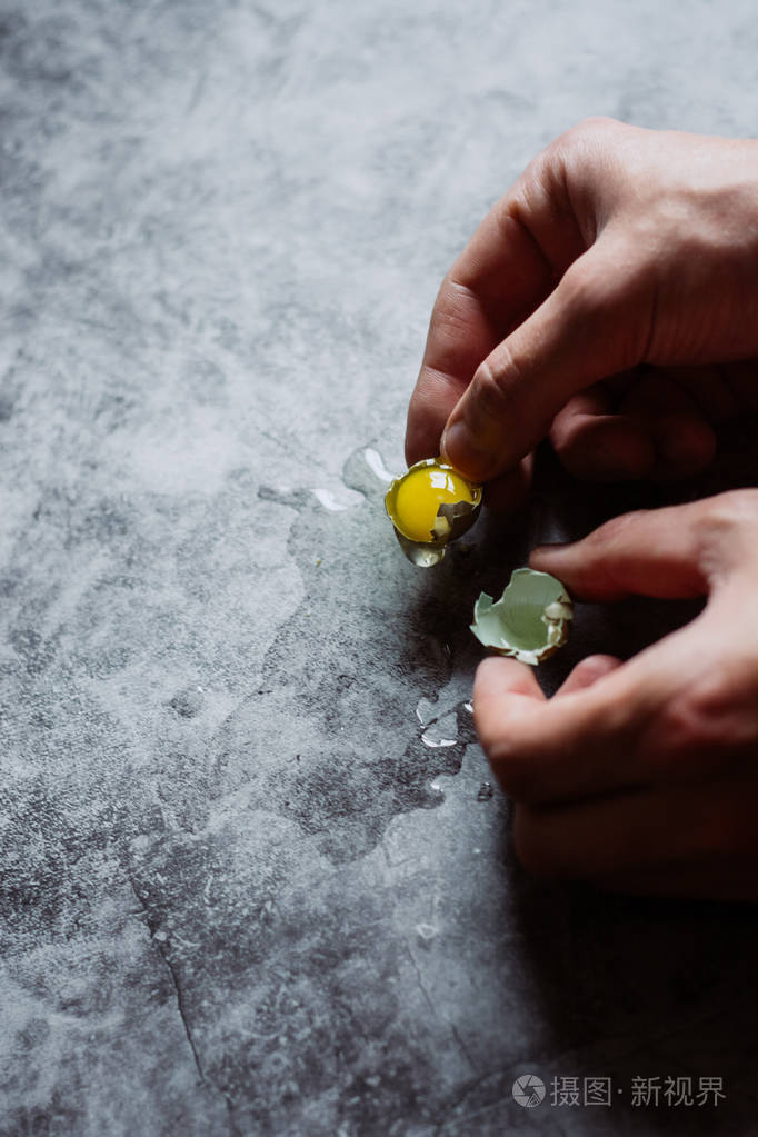 男人手里拿着小的生碎鹌鹑蛋深色混凝土背景
