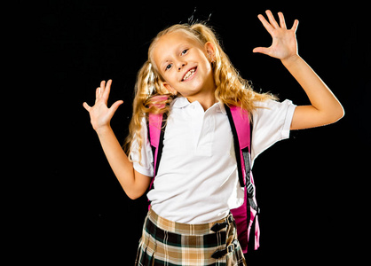 可爱漂亮的小女生背着粉红色的大书包,在黑色的背景下感到兴奋和快乐