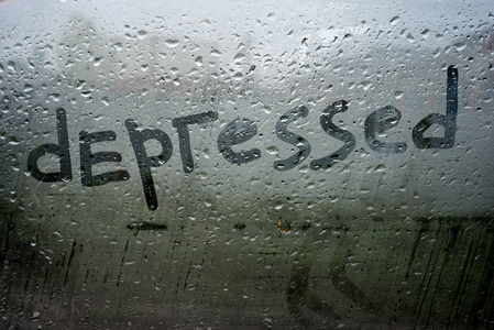 不字写在玻璃窗上的"郁闷"字,雨滴在冰冷黑暗的色调中,表达了悲伤的