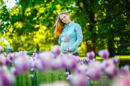 自然背景下的孕妇。 有肚子的漂亮女孩模特