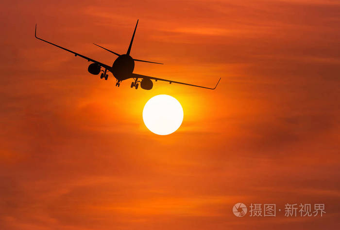 剪影客机在日落时高空飞向天空