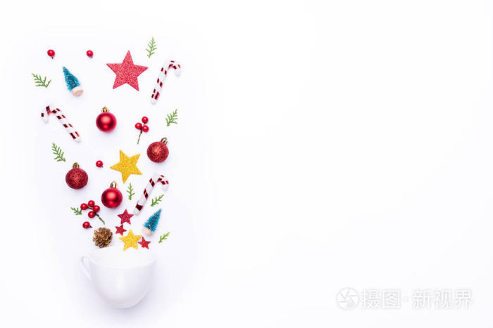 圣诞节背景概念。顶部的白色杯子溅出圣诞装饰与礼品盒云杉枝，松果，红色浆果和铃铛在白色背景。