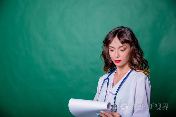 肖像美丽的女医生微笑着, 并填写了一个医学图表上的绿色背景与复制空间。健康和医疗理念。医生填充处方在剪贴板上分离。美丽的