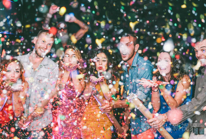 快乐的朋友在聚会上扔纸屑在俱乐部千禧一代年轻人在夜总会欢乐庆祝夜