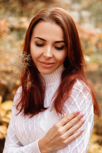 秋天叶子背景的礼服和帽子的妇女