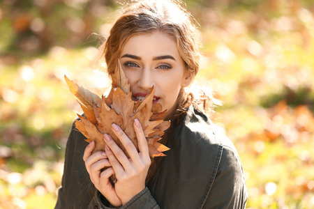秋天公园有叶子的美丽的年轻女子
