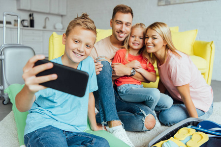 快乐的家庭在暑假打包的时候，在智能手机上自拍