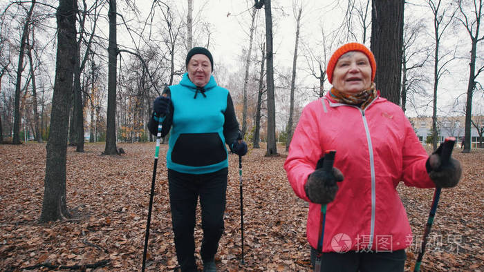 两名老年妇女走在北欧行走的棍子上