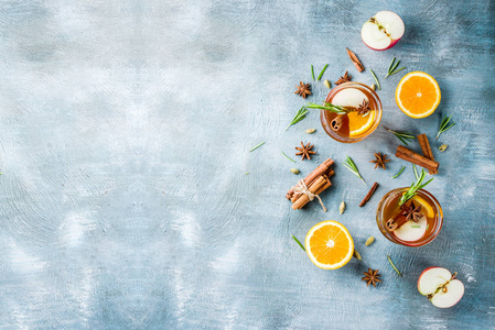 传统的冬季饮料用白葡萄酒和香料苹果橙覆盖葡萄酒鸡尾酒。 在浅蓝色的桌子上