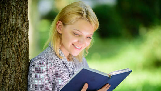 最好的自助书籍的妇女。女孩感兴趣坐公园读书自然背景。阅读鼓舞人心的书籍。女性文学。每个女孩都应该读书。放松休闲爱好概念