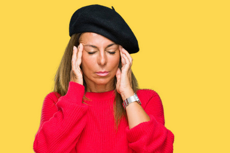 中年成年女性穿着时尚贝雷帽在孤立的背景上，手在头上疼痛，因为压力。 偏头痛。