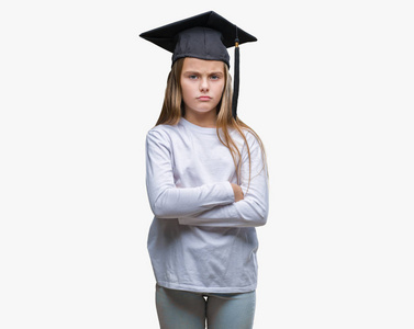 年轻漂亮的女孩戴着研究生帽，在孤立的背景怀疑和紧张的不赞成的表情上，交叉的手臂。 消极的人。