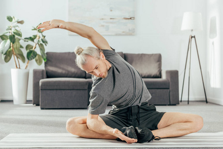 运动的成年男子在家中练习和伸展瑜伽垫