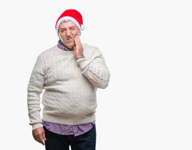 英俊的老人戴着圣诞帽，戴着孤立的背景，用手摸着嘴，表情痛苦，因为牙痛或牙齿上的牙齿疾病。 牙医的概念。