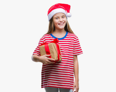 年轻漂亮的女孩戴着圣诞帽，拿着礼物在孤立的背景上，快乐的脸站着，微笑着，露出自信的微笑，露出牙齿
