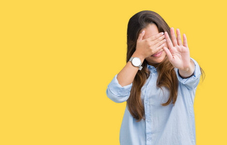 年轻美丽的黑发商务女性在孤立的背景上,用手遮住眼睛,用悲伤和恐惧的