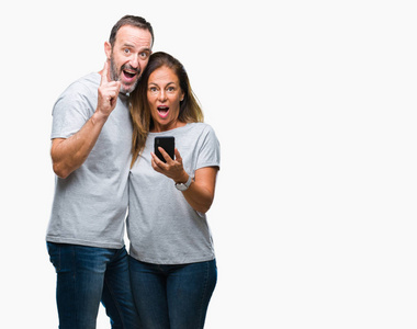 中年西班牙裔夫妇在智能手机上发短信，背景偏远，对一个想法或问题感到惊讶，用手指指着一张快乐的脸第一