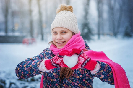 冬天公园里一个笑的少年女孩抱着一颗雪白的心。