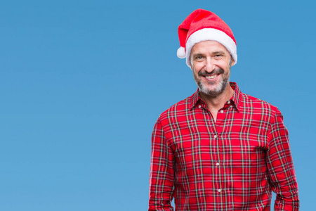 中年老人戴着圣诞帽，在孤立的背景上，脸上带着快乐和凉爽的微笑。 幸运的人。