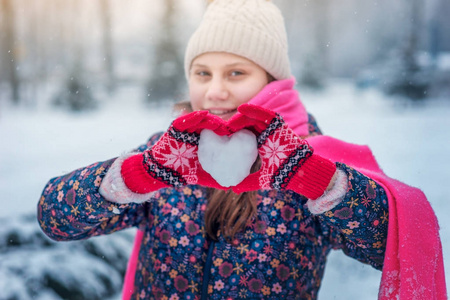 冬天公园里一个笑的少年女孩抱着一颗雪白的心。