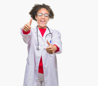 年轻的AFRO美国医生女人在孤立的背景下，赞成用手竖起大拇指做积极的手势，微笑着，为成功而高兴。 看着相机赢家的手势。