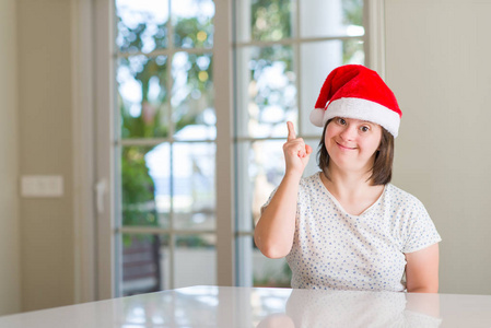 家庭主妇戴着圣诞帽惊讶地想到了一个主意或问题，用手指指着幸福的第一面