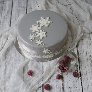 法国覆盆子慕斯蛋糕与新的岁月装饰雪花和白色的树枝在白色的木制背景。 圣诞蛋糕。 斯堪的纳维亚风格。 关闭复制空间选择性聚焦